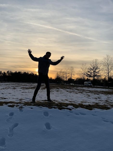 A person exercising outdoors in a snowy environment, with sunlight breaking through the clouds, symbolizing the benefit of outdoor activities and natural light exposure during winter for combating SAD.