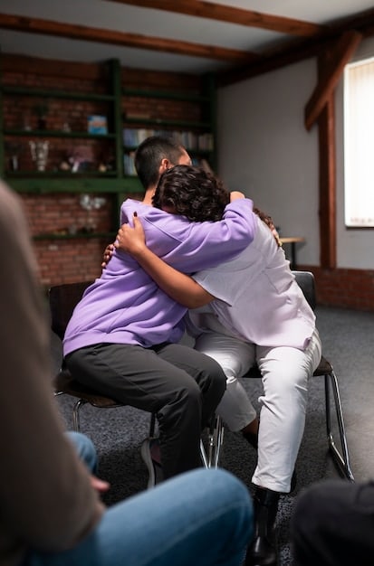 A person receiving a comforting hug from a friend, set against the backdrop of a supportive community event in the US, highlighting the tangible benefits of a strong support network.