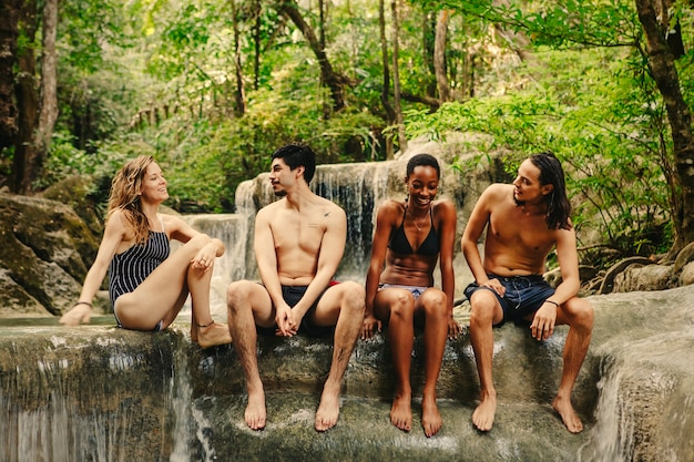 A diverse group of people participating in a group forest bathing session. They are walking slowly through a dense forest, touching trees, and breathing deeply. The atmosphere is peaceful and communal.