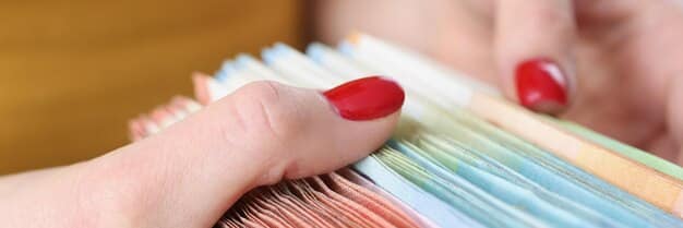 A close-up shot of a hand organizing various tax documents such as W-2 forms, social security cards, and bank statements in a folder. The image highlights the importance of preparation for tax season.