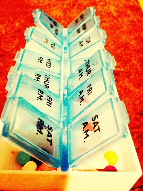 A close-up of an automated pill dispenser with clearly labeled compartments for different times of the day and a digital display showing the next dispensing time.