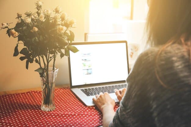 A woman is using a laptop at a table, looking at an online directory of caregiver support groups in her local area. The screen shows various listings with contact information and meeting schedules. The setting is a cozy home office, emphasizing the convenience of searching for support online.