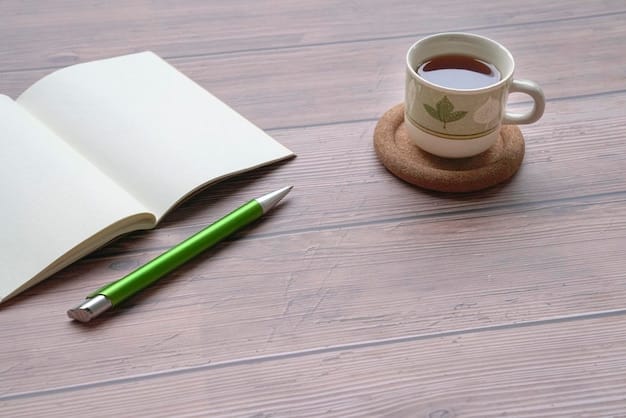 A journal and pen rest on a wooden desk next to a cup of tea, suggesting reflective writing and self-care practices.