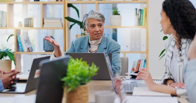 A caregiver and a program administrator sitting at a table, reviewing a document together. The setting is a well-lit office with filing cabinets in the background